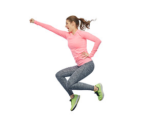 Image showing happy smiling sporty young woman jumping in air