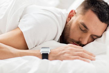 Image showing close up of man with smartwatch sleeping in bed