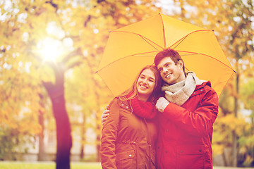 Image showing smiling couple with umbrella in autumn park