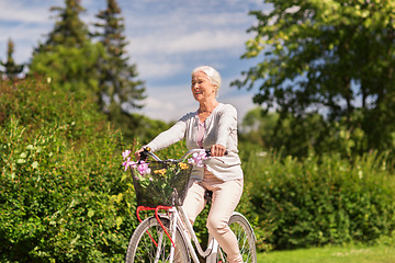 Image showing happy senior woman riding bicycle at summer park