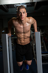 Image showing man doing triceps dip on parallel bars in gym