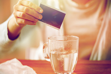 Image showing woman pouring medication into cup of water