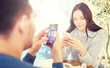 Image showing happy couple with smartphones drinking tea at cafe