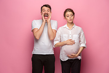 Image showing The funny surprised handsome man and his beautiful pregnant wife\'s tummy