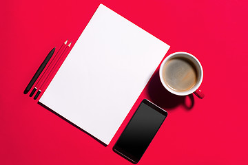 Image showing Modern red office desk table with smartphone and cup of coffee.