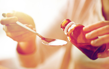 Image showing woman pouring medication from bottle to spoon