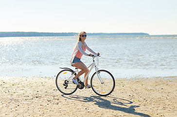 Image showing happy woman riding bicycle along summer beach