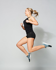 Image showing young woman in black sportswear jumping
