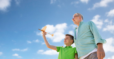Image showing senior man and boy with toy airplane over sky