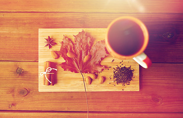 Image showing cup of tea, maple leaf and almond on wooden board