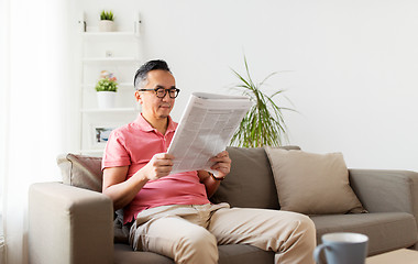 Image showing asian man in glasses reading newspaper at home