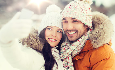 Image showing happy couple taking selfie by smartphone in winter