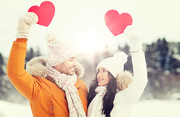 Image showing happy couple with red hearts over winter landscape