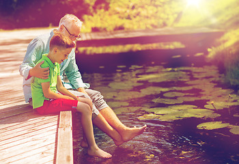 Image showing grandfather and grandson sitting on river berth