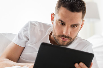 Image showing close up of man with tablet pc in bed at home