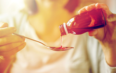 Image showing woman pouring medication from bottle to spoon