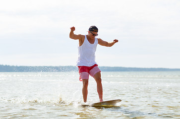 Image showing young man riding on skimboard on summer beach
