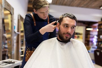 Image showing man and barber with trimmer cutting hair at salon