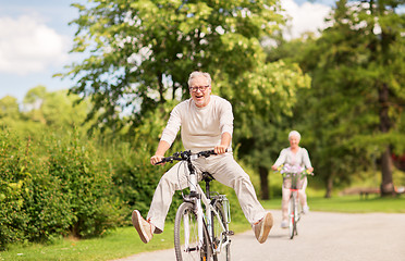 Image showing happy senior couple riding bicycles at summer park