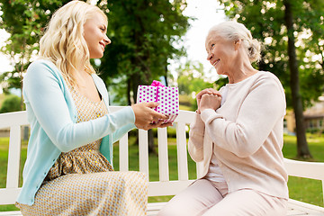 Image showing daughter giving present to senior mother at park