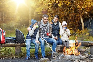 Image showing happy family sitting on bench at camp fire