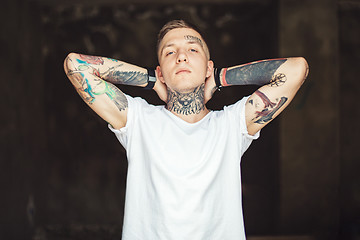 Image showing Confident tattooed man posing outside