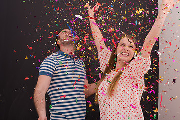 Image showing couple blowing confetti in the air isolated over gray