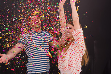 Image showing couple blowing confetti in the air isolated over gray