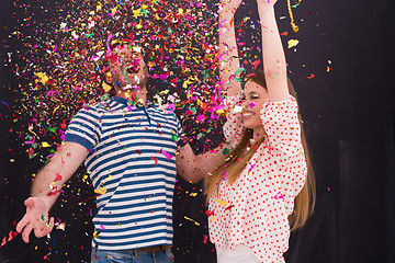 Image showing couple blowing confetti in the air isolated over gray