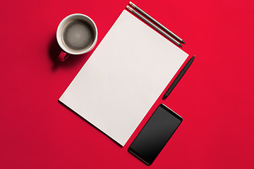 Image showing Modern red office desk table with smartphone and cup of coffee.