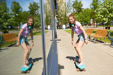 Image showing happy teenage girl riding on longboard in summer