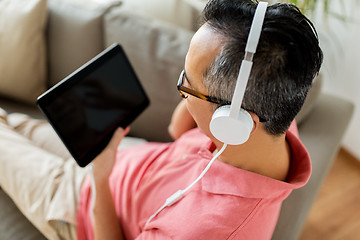 Image showing man with tablet pc and headphones at home