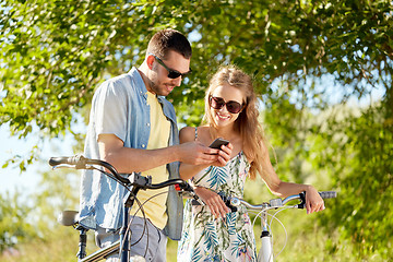 Image showing happy couple with bicycles and smartphone outdoors