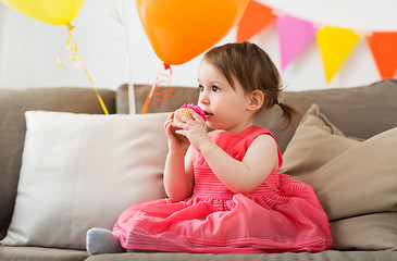 Image showing happy baby girl eating cupcake on birthday party