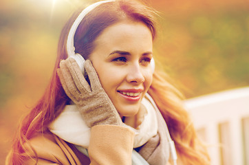 Image showing happy woman with headphones in autumn park