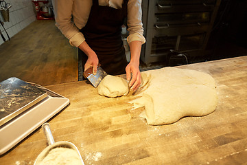 Image showing baker portioning dough with bench cutter at bakery