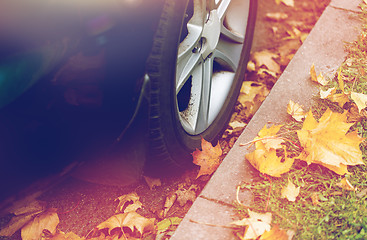 Image showing close up of car wheel and autumn leaves
