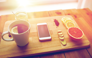 Image showing smartphone with cup of lemon tea, honey and ginger