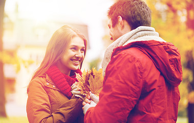 Image showing happy couple with maple leaves in autumn park