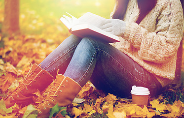 Image showing woman with book drinking coffee in autumn park