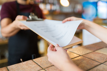 Image showing bartender showing menu to customer at bar