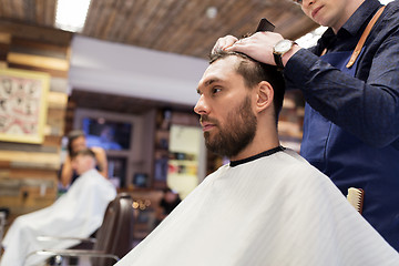 Image showing man and barber cutting hair at barbershop