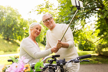 Image showing senior couple with bicycles taking selfie at park