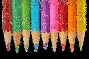 Image showing Colorful pencils close-up into water with bubbles