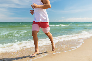 Image showing happy man running along summer beach