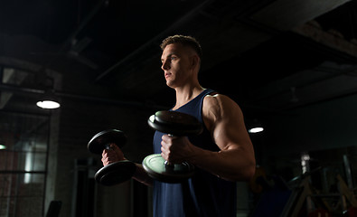Image showing young man with dumbbells exercising in gym