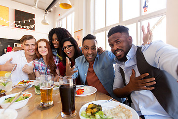 Image showing happy friends taking selfie at restaurant or bar