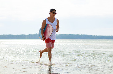 Image showing happy young man with skimboard on summer beach