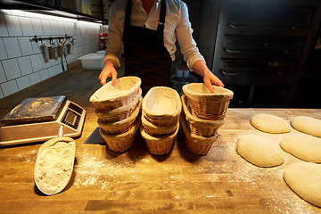 Image showing baker with baskets for bread dough at bakery