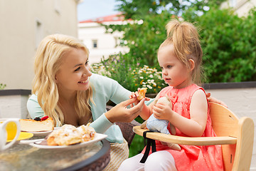 Image showing happy mother feeding daughter with cake at cafe